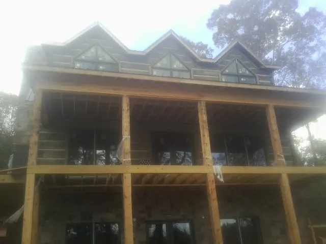 Dormers and porch framing on a large log home under construction — Roof Coating work by our crew in Steens