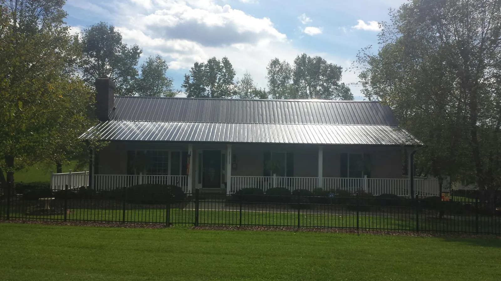 Gray metal roof on a brick ranch with a full width front porch — Gutter Guard Installation work by our crew in Steens