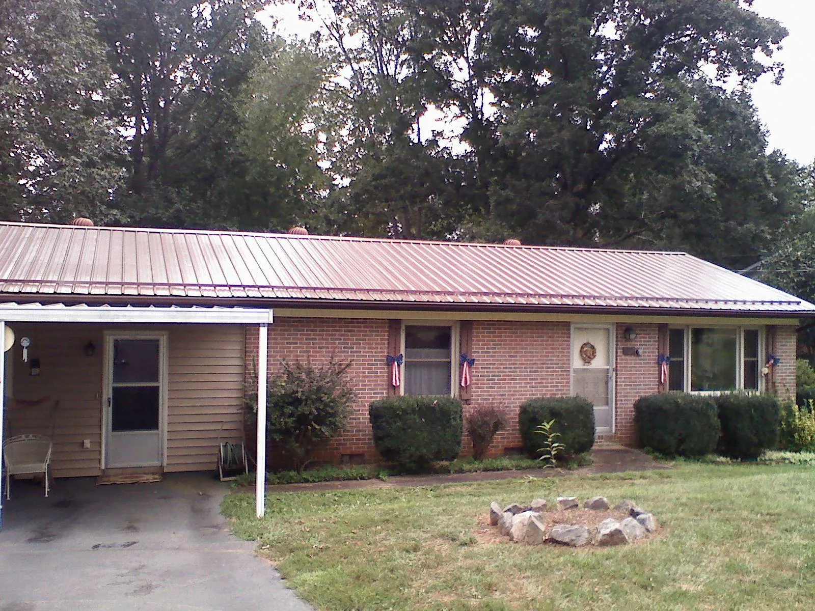 Bronze metal roof and carport on a brick ranch home — Roof Repair work by our crew in Steens